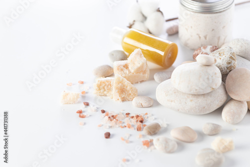 body and soul care, round stones, sea salt, peeling cream, body oil, cotton flowers on a white background