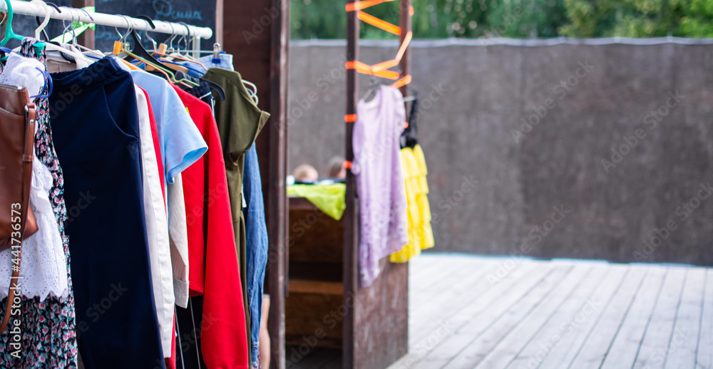 Colorful secondhand clothes on hangers at local market on the street