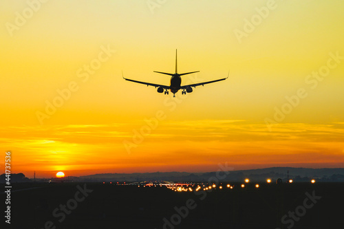 Airplane landing on the runway during sunset and dusk