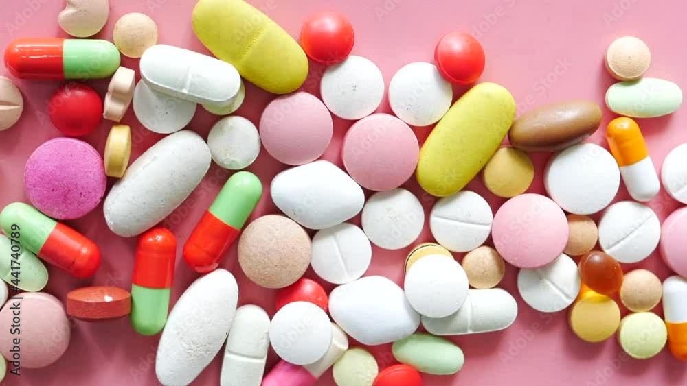 Close up of many colorful pills and capsules on pink background Close up of many colorful pills and capsules on pink background