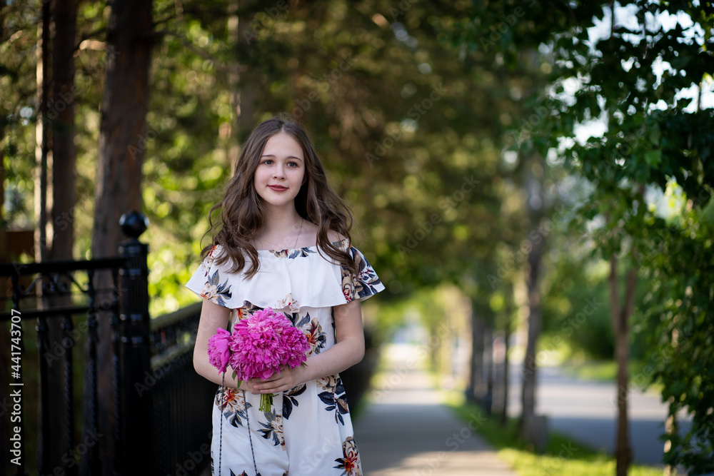 cheerful girl in a light summer dress against the background of a city park cheerful girl in a light summer dress against the background of a city park