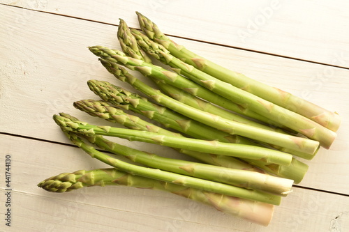 Several stalks of green organic asparagus on a wooden table, close-up, top view.