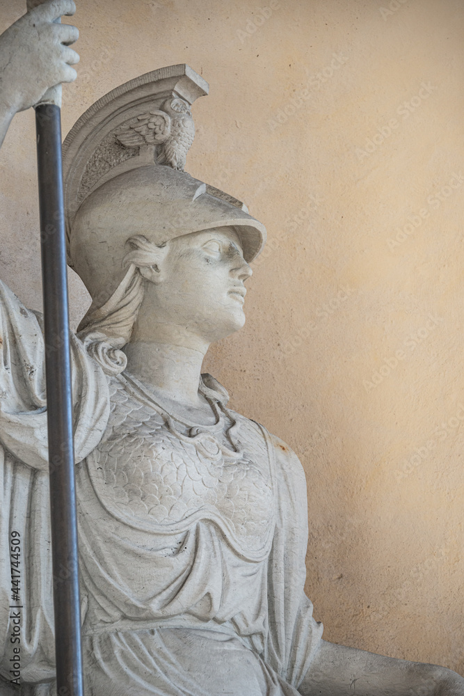 Old statue of a sensual Roman woman warrior, Amazonian, as defender with spear and helmet, details, closeup, with copy space.