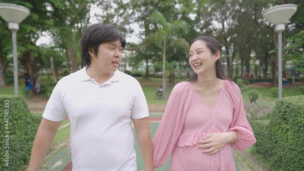 Happy family in the park, young adult asian couple holding hands walking inside outdoor park, family bonding love support relationship, positive emotion, importance of maternal health during pregnancy Happy family in the park, young adult asian couple holding hands walking inside outdoor park, family bonding love support relationship, positive emotion, importance of maternal health during pregnancy