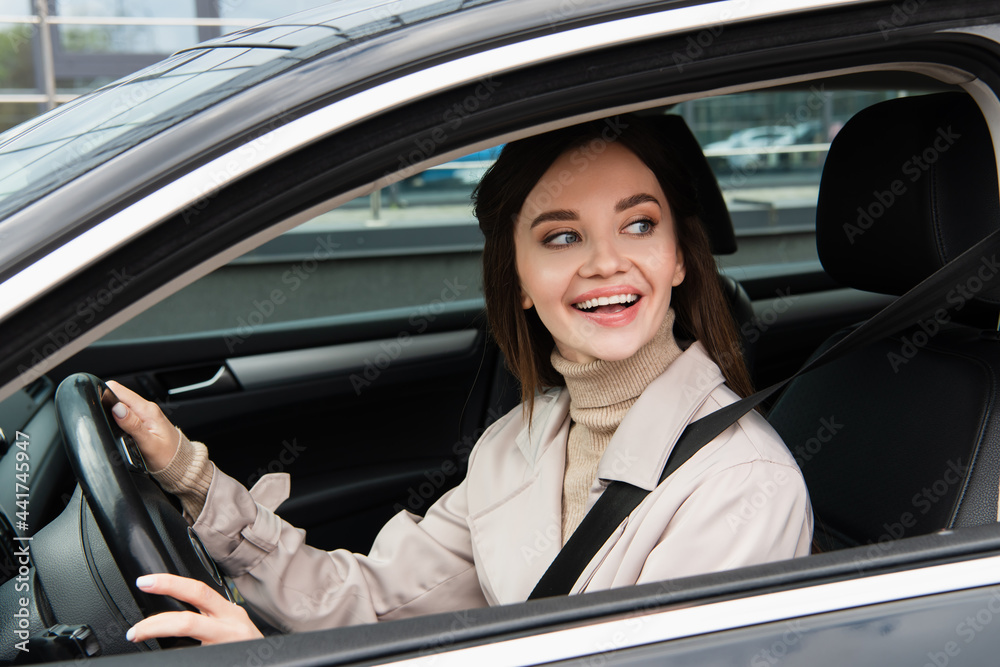 cheerful young woman looking away while driving automobile