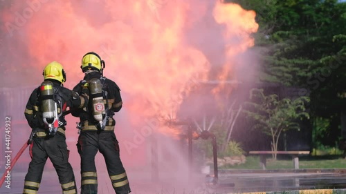 Firefighter team help and support to extinguish huge fire from gas pipe by using water to spray cover the area in field during practice of training at station.