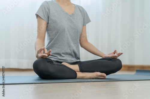Meditating,asian young woman, girl practice yoga in lotus position, calm pose for meditation, exercise on mat for wellbeing, healthy care in room at home. Workout fitness exercise, sport in sportswear