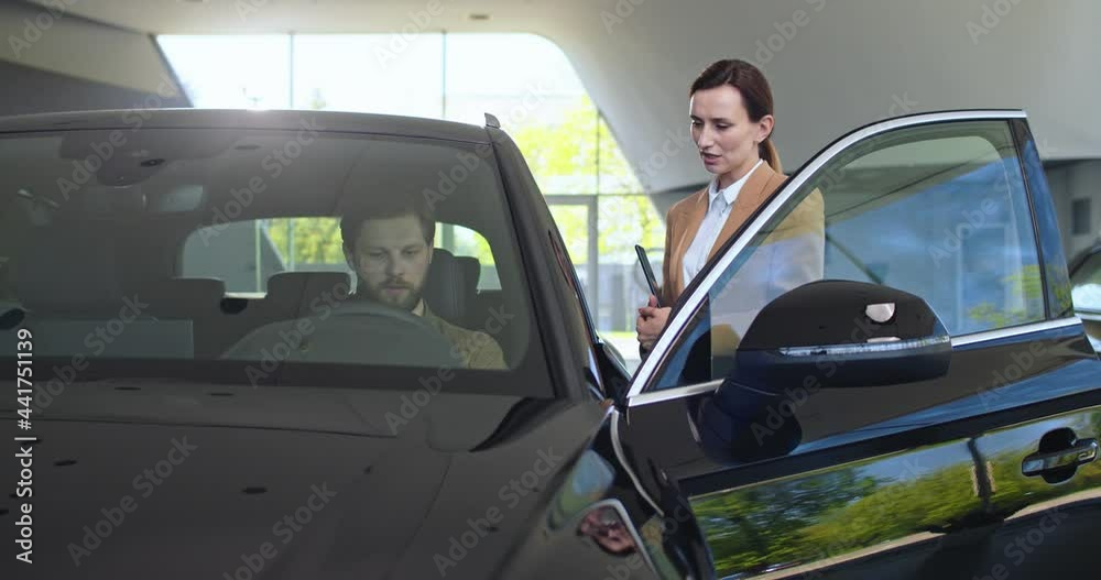 Showroom car, buyer sit in automobile and test it, saleswoman manager help client. Showroom car, buyer sit in automobile and test it, saleswoman manager help client.