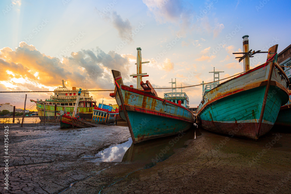 Wrecks of fishing boats stranded and beautiful skies,Many boats moored in sunrise morning time at Chalong port, Main port for travel ship to krabi and phi phi island, Phuket, Thailand
