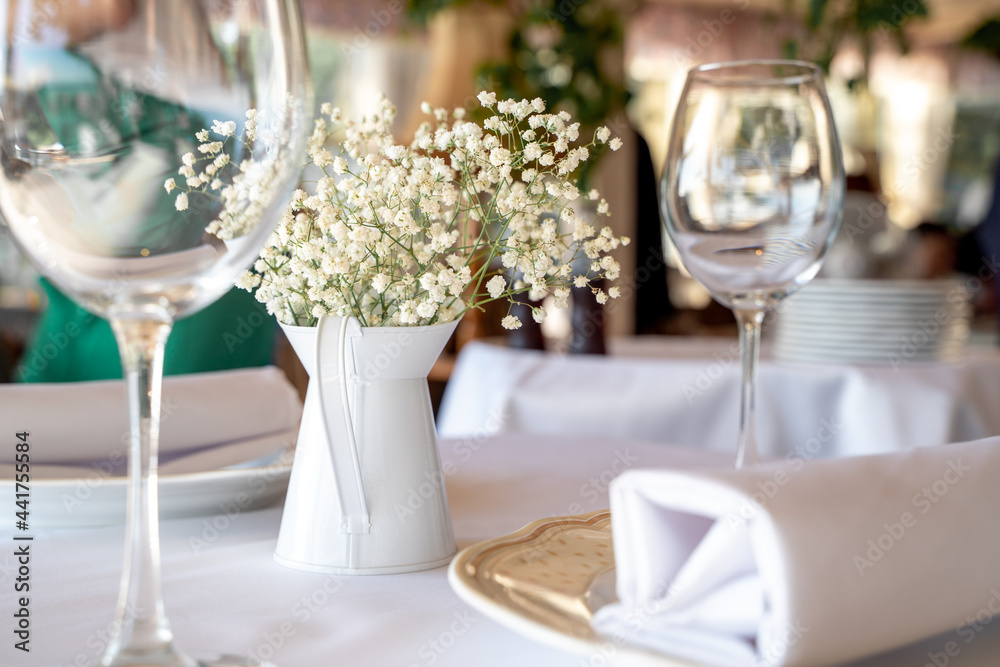 
a beautiful set table with dishes and glasses and a branch of gypsophila