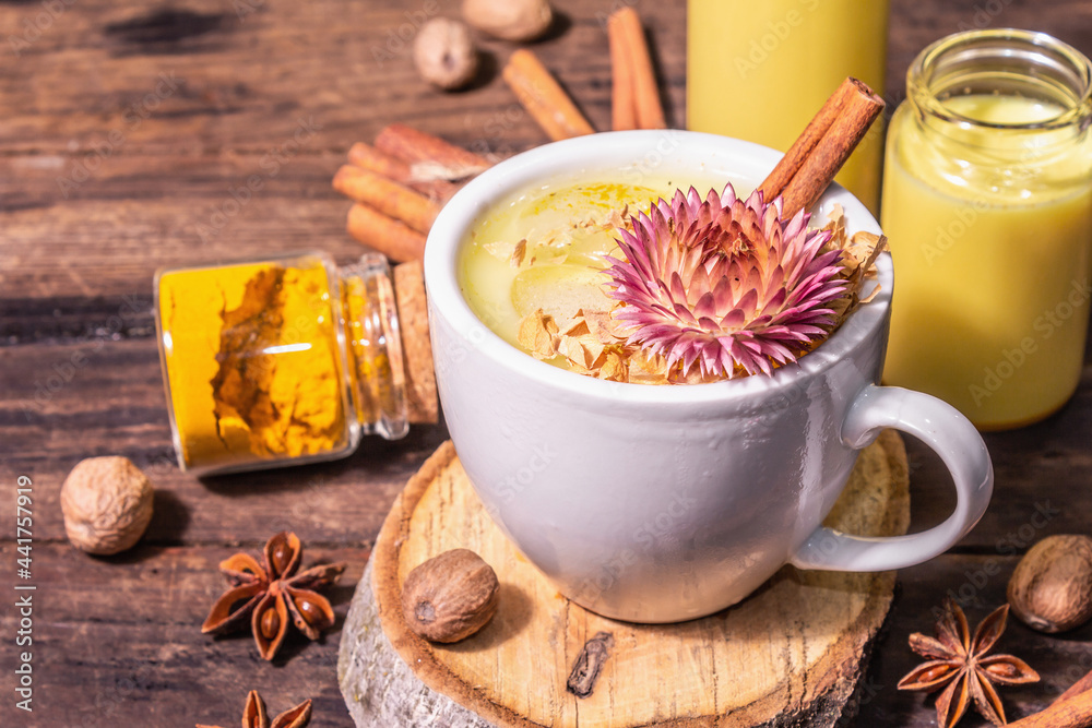 Golden turmeric milk with ice on bright yellow background Golden turmeric milk with ice on bright yellow background