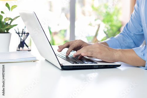 The hand of the office manager uses a laptop keyboard while working.