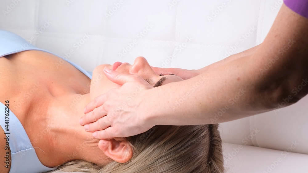 Facial massage beauty treatment. Close up of a young womans face lying on back, getting face lifting massage, pinch and roll technique Facial massage beauty treatment. Close up of a young womans face lying on back, getting face lifting massage, pinch and roll technique
