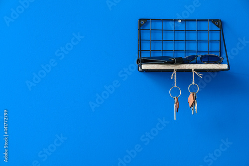 Shelf with accessories and keys hanging on color wall