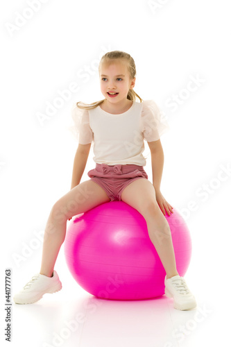 Little girl plays with a big ball for fitness