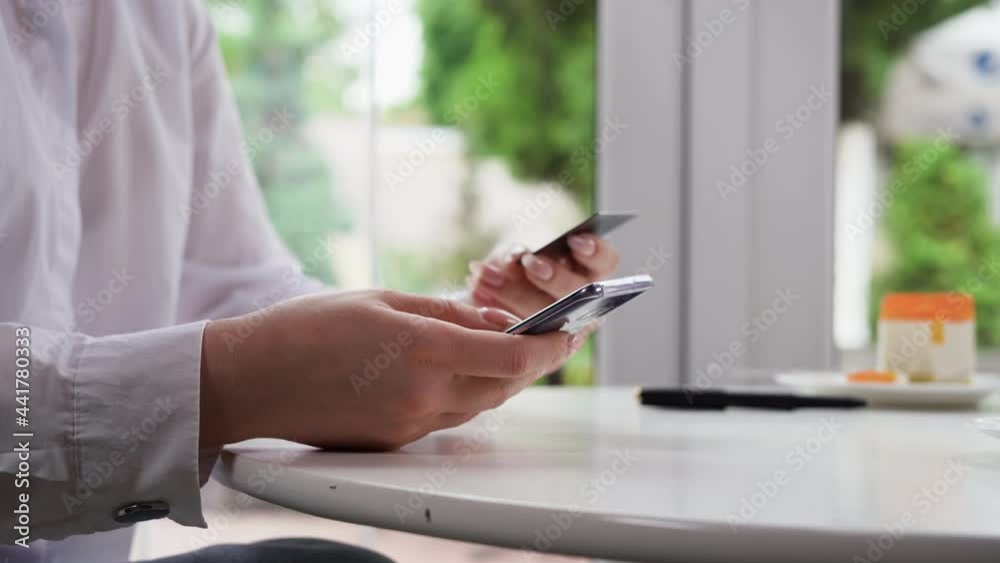 Close up hands holding credit card and using mobile smart phone while sitting at a table in cafe, online shopping, woman happy. Close up hands holding credit card and using mobile smart phone while sitting at a table in cafe, online shopping, woman happy.