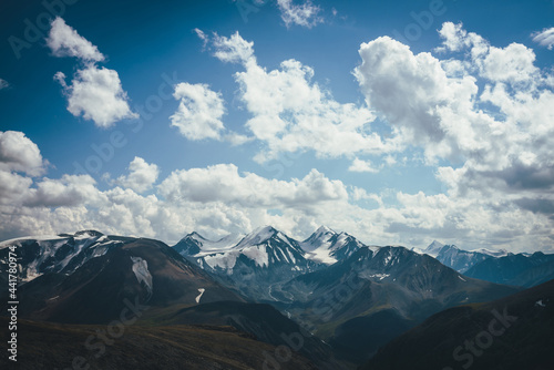 Awesome alpine view to big snowy mountains with glacier. Wonderful highland scenery with great snowy mountains and clouds in blue sky. Amazing mountain landscape with glaciers and melt water streams.