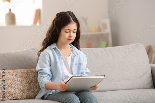 Little girl reading book at home