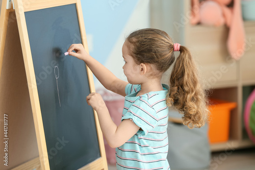 Little girl drawing on blac...