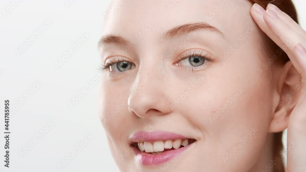 Big close-up shot of good-looking European young red-haired woman touches her face smiling wide for the camera on white background | Skin hydration concept Big close-up shot of good-looking European young red-haired woman touches her face smiling wide for the camera on white background | Skin hydration concept