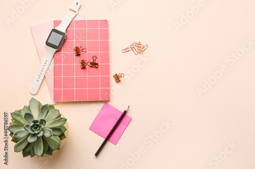 Different office tools and smartwatch on color table © Pixel-Shot