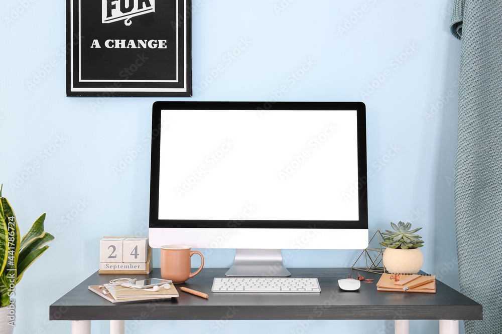 Stylish workplace with modern computer on table near color wall Stylish workplace with modern computer on table near color wall