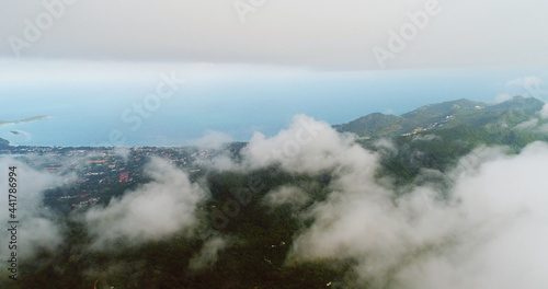 AERIAL. Flight above tropical island throught clouds and top view of mountains and forest. Thailand. © skymediapro