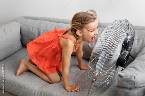 Silly young girl screaming in front of a fan photo