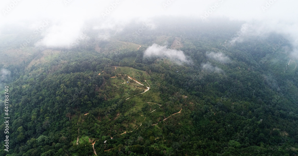 AERIAL. Flight above tropical island throught clouds and top view of mountains and forest. Thailand.