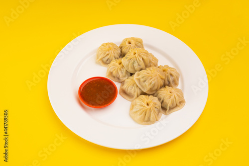 Plate of nepali veg momo served with tomato sauce, chutney.  photo