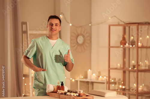 Male massage therapist showing thumb-up in spa salon