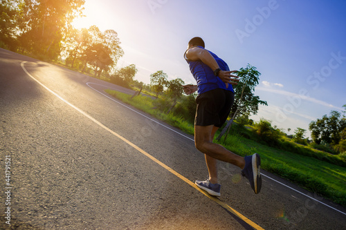 Silhouette of Young man running sprinting on road. Fit runner fitness runner during outdoor workout with sunset background. Selected focus.