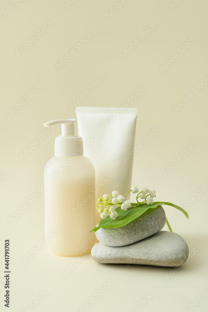 Composition with cosmetic products, stones and lily-of-the-valley flowers on color background