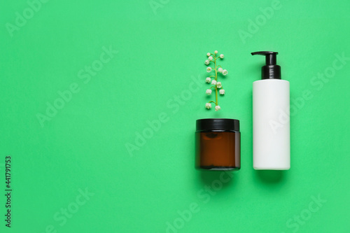 Cosmetic products and lily-of-the-valley flowers on color background