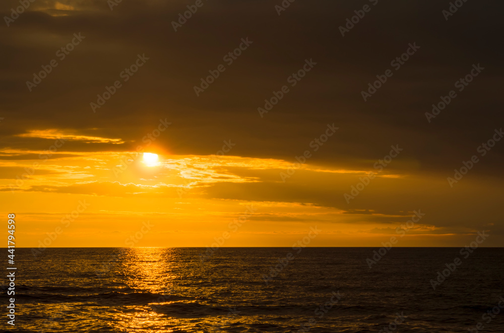 Obraz premium Beautiful summer sunset over the baltic sea. The sun's rays pass through the clouds