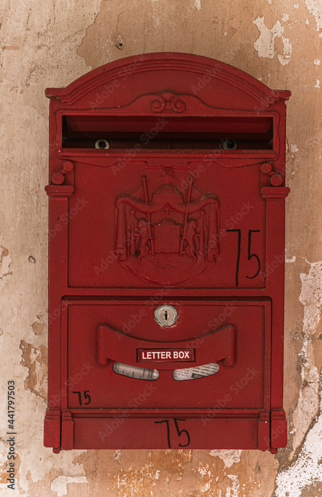 Czerwona skrzynka pocztowa na listy na tle starego budynku.