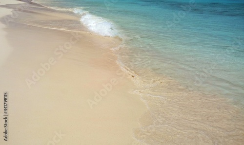 Beautiful turquoise ocean water, light waves hitting the white sandy tropical beach