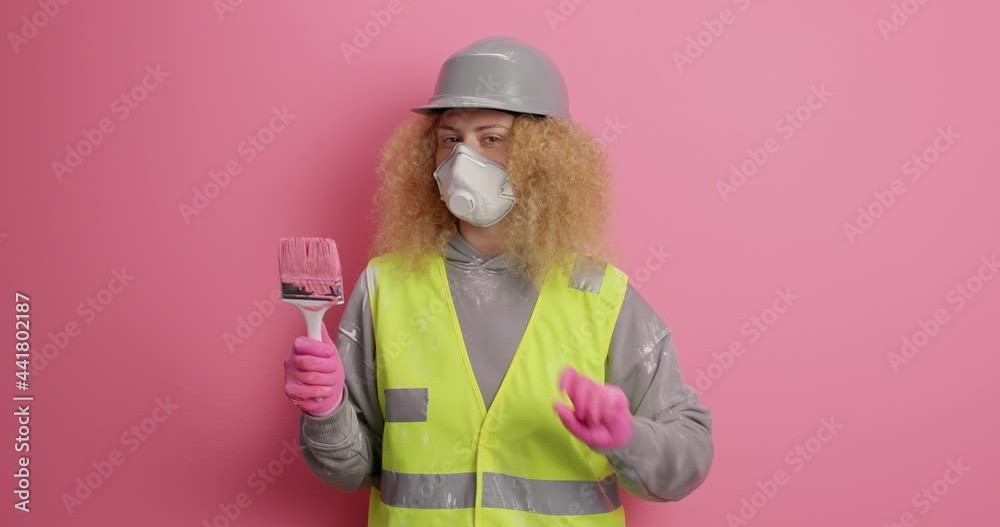Serious woman maintenance worker shakes head says no raises index finger for making refusal gesture holds painting brush doesnt need somebodys help wears uniform isolated on pink studio wall Serious woman maintenance worker shakes head says no raises index finger for making refusal gesture holds painting brush doesnt need somebodys help wears uniform isolated on pink studio wall