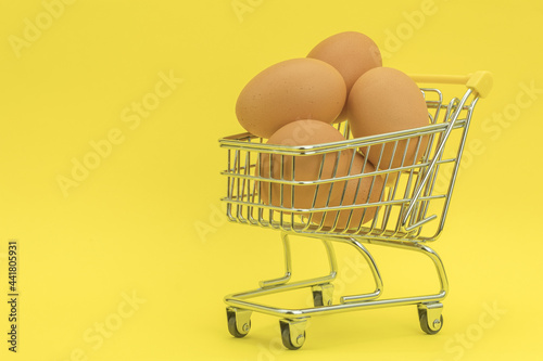 Raw chicken eggs in a basket on a yellow background