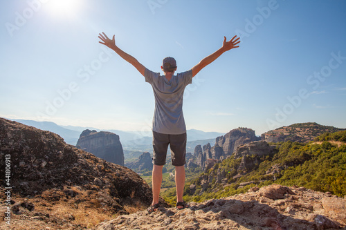 Happy man traveller standing with hands up in mountain