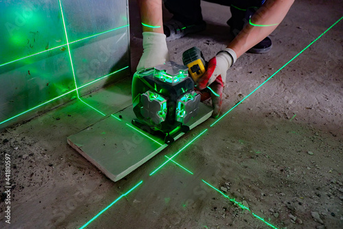 the builder measures the repair lines using a green laser level