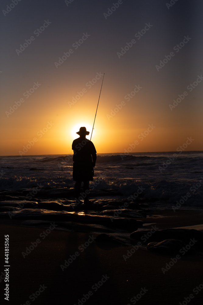 Fisherman at sunrise on the edge of the ocean