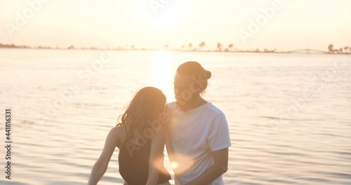 Romantic young couple is dancing on seaside, beach in golden hour sunset. Happy woman and man's relationship. Happiness, relaxing concept.