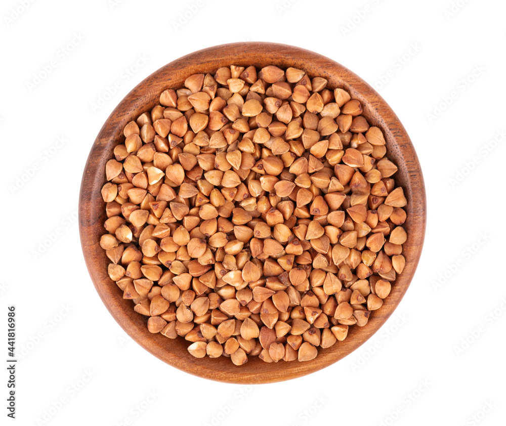 Roasted buckwheat grains in wooden bowl, isolated on white background. Dry brown buckwheat groats. Top view. Roasted buckwheat grains in wooden bowl, isolated on white background. Dry brown buckwheat groats. Top view.