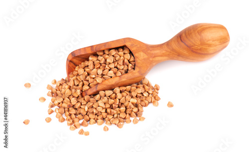 Roasted buckwheat grains in olive scoop, isolated on white background. Dry brown buckwheat groats.