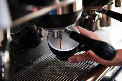 Close-up of espresso pouring from steam coffee machine into cups. Professional coffee brewing.