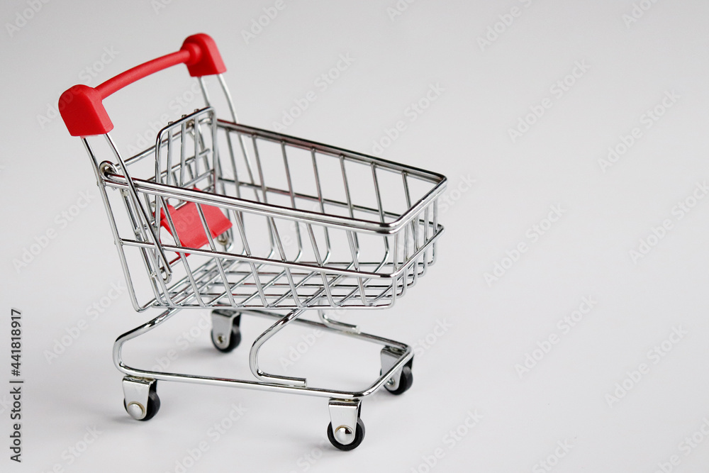 Shopping cart on a white background. A small supermarket cart. The concept of a store, sales, purchases.