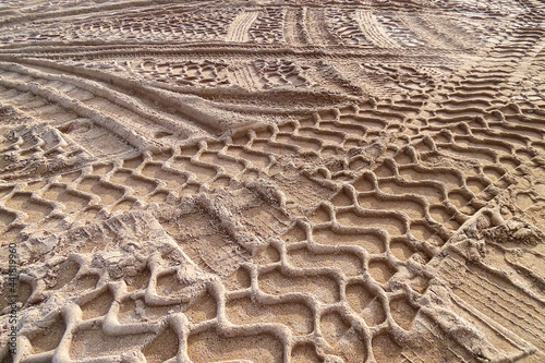 Sandiger goldener Boden mit großen Reifenspuren im Relief. Spuren im Sand. Viel befahrener belebter Sandstrand im Freien. Sandgrube; Sandabbaugebiet in Deutschland. photo