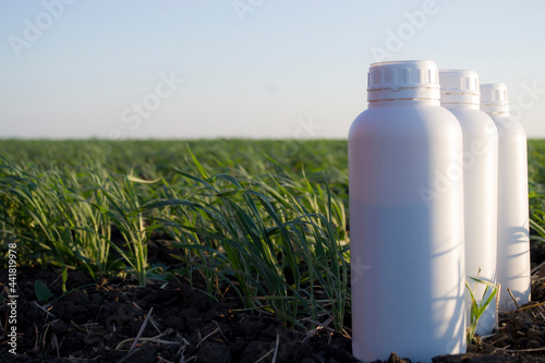 White canister against the background of agriculture, canisters from under different types of chemical products.