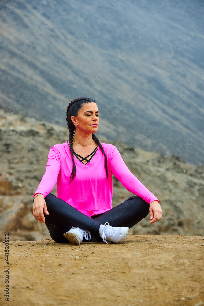 Fototapeta premium mature woman meditating on the mountain in sportswear